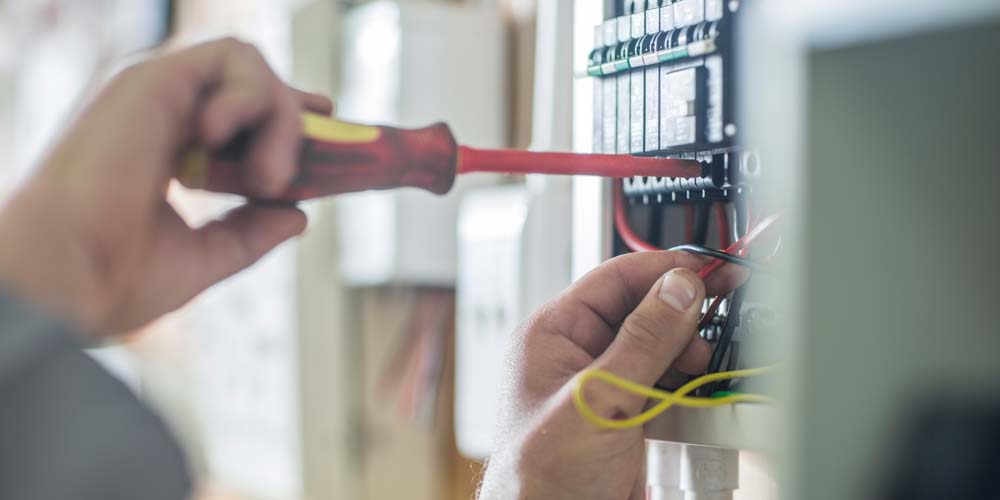 Elektriker som skruvar i ett skåp